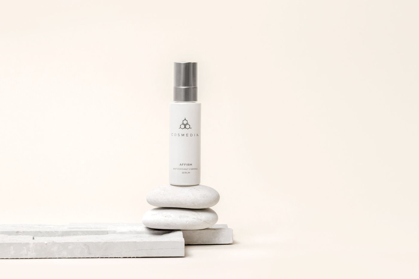 COSMEDIX serum resting on smooth stones